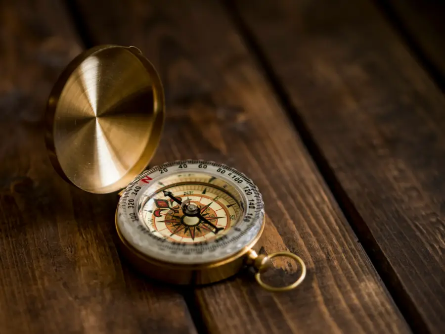 Brass Pocket Compass on wooden surface | Photo by Damian Karpiński on Unsplash